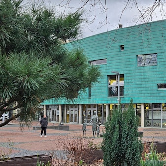 Ein großes Gebäude in der Form eines Schiffbugs mit grüner Fassade.