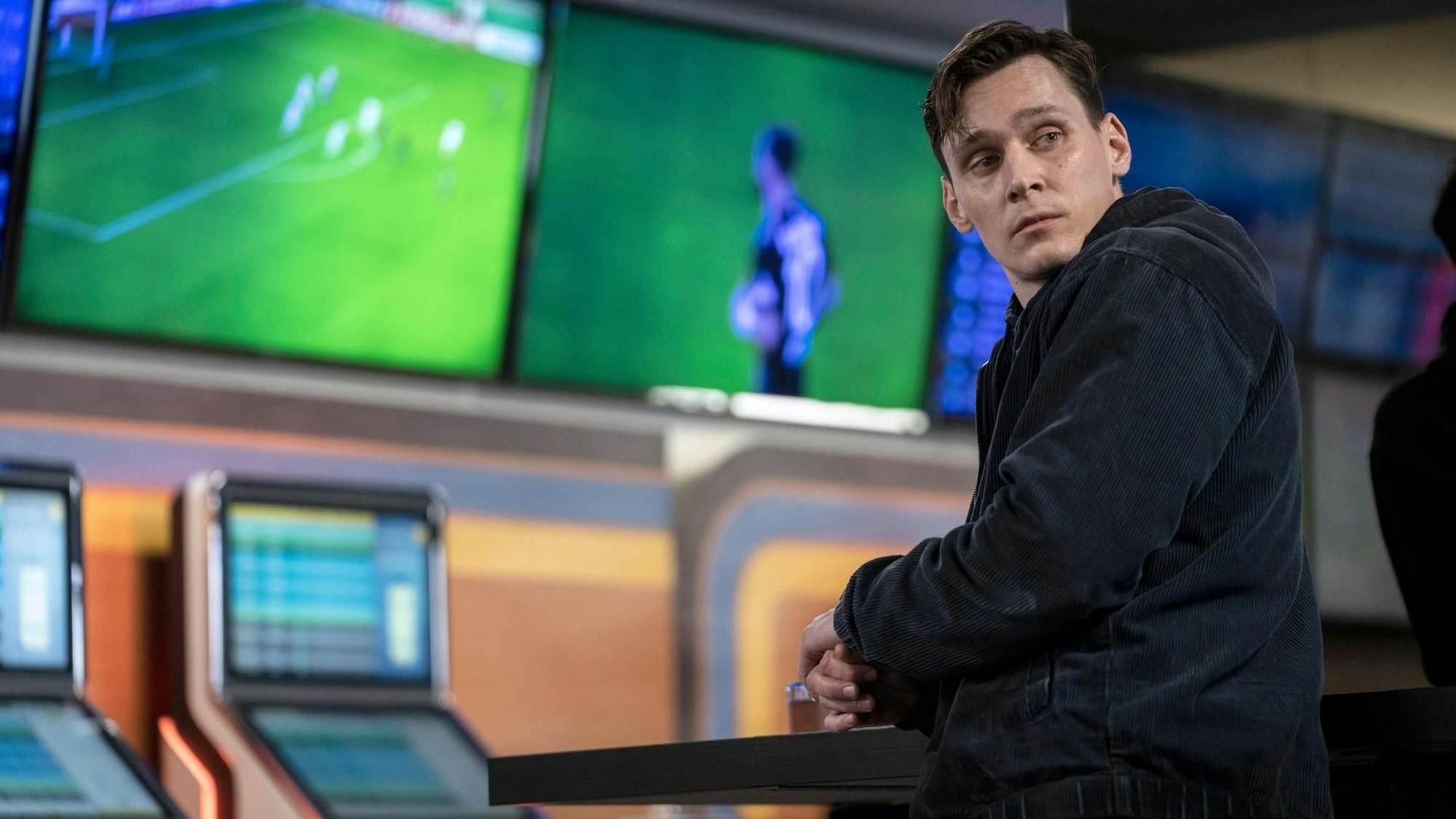 Jan Pawlek in einem Wettbüro vor Fernsehern und Spielautomaten