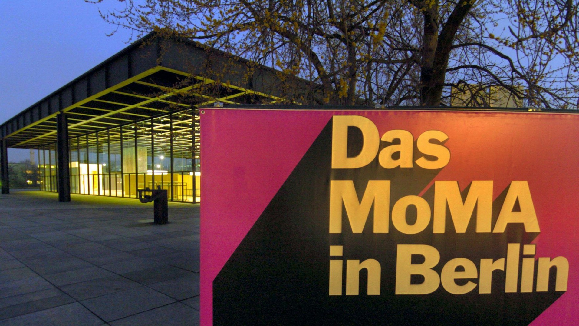 Vom Licht der Autoscheinwerfer erleuchtet, steht am Sonntag (15.02.2004) vor der Neuen Nationalgalerie in Berlin ein Plakat mit der Aufschrift "Das MoMA in Berlin", mit dem auf eine Ausstellung mit Exponaten aus dem Museum of Modern Art (MoMA) hingewiesen wird.