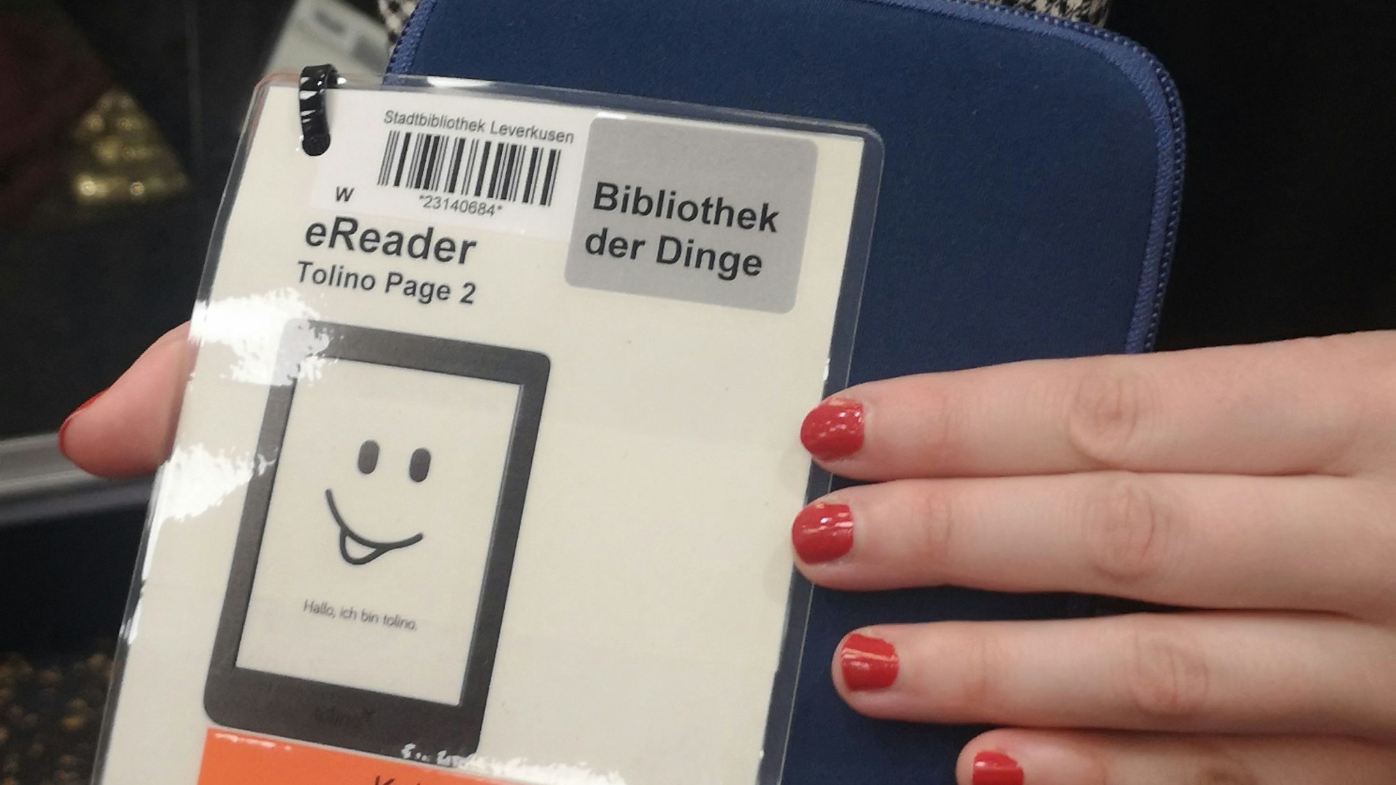 Eine Frau hält einen eReader mit dem Barcode der Bibliothek in der Hand.