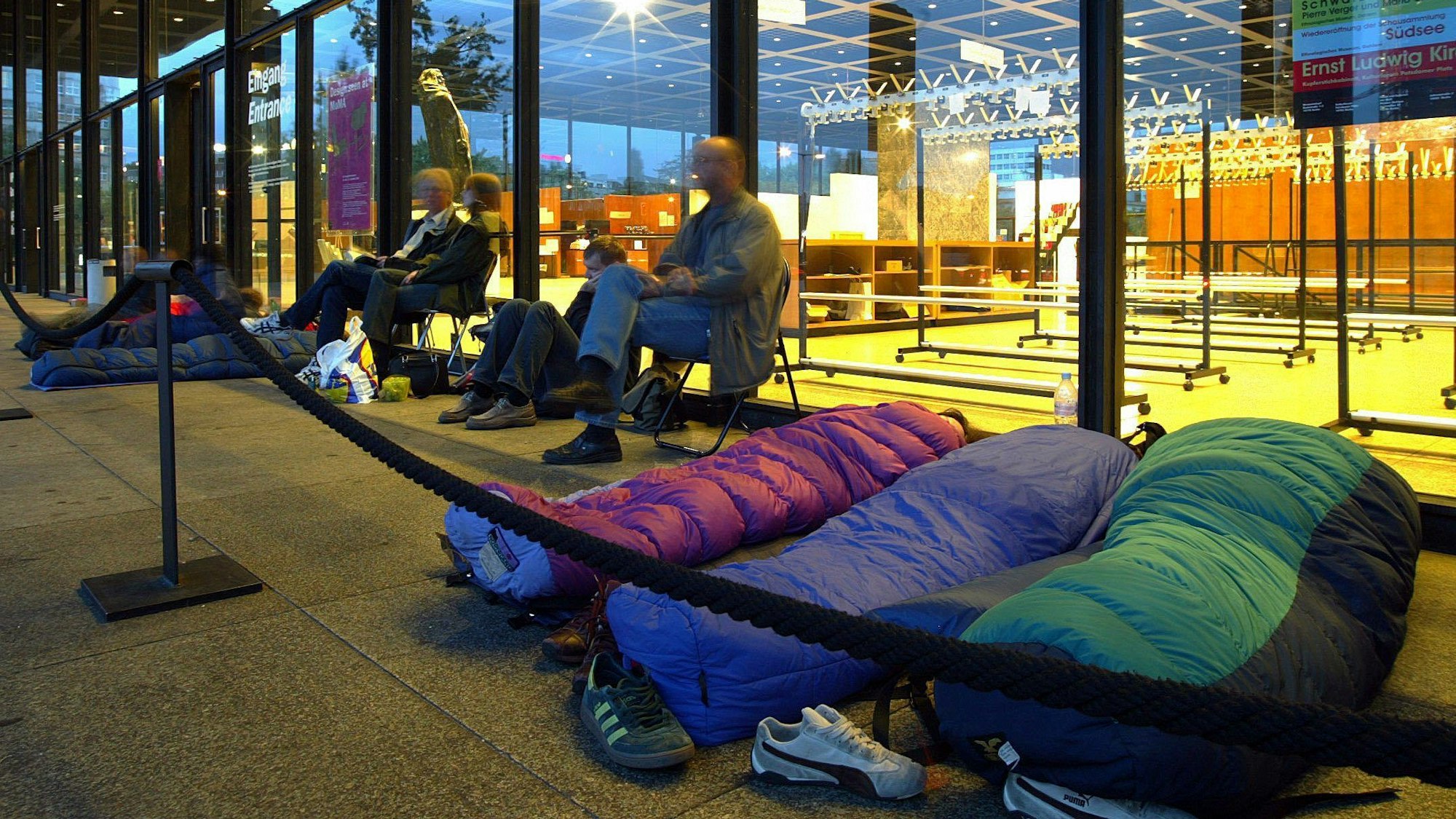 27.08.2004, Berlin: In ihren Schlafsäcken liegend und auf Stühlen sitzend warten Besucher in den frühen Morgenstunden in Berlin auf den Einlass zur Ausstellung des Museum of Modern Art (MoMA) in der Neuen Nationalgalerie.