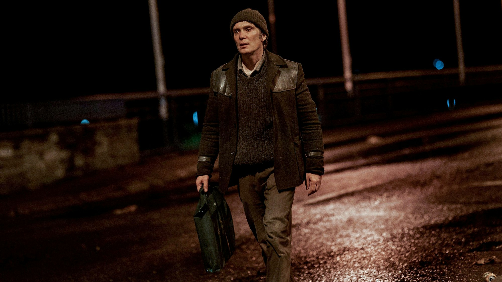 Ein Mann geht nachts über eine Straße.