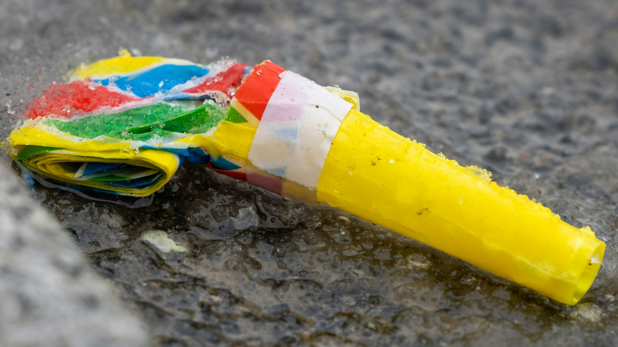 Eine vom Regen durchnässte Karnevalströte liegt an einem Straßenrand. (Symbolbild)