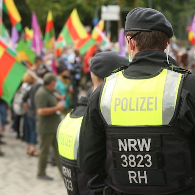 Ein Polizist steht mit dem Rücken zur Kamera vor einer Gruppe Demonstranten.