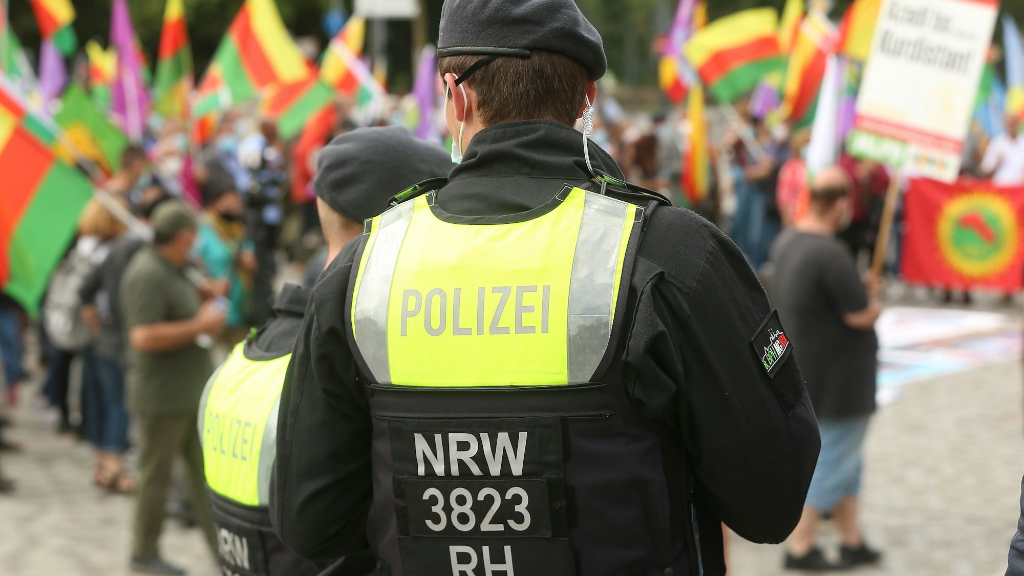 Ein Polizist steht mit dem Rücken zur Kamera vor einer Gruppe Demonstranten.
