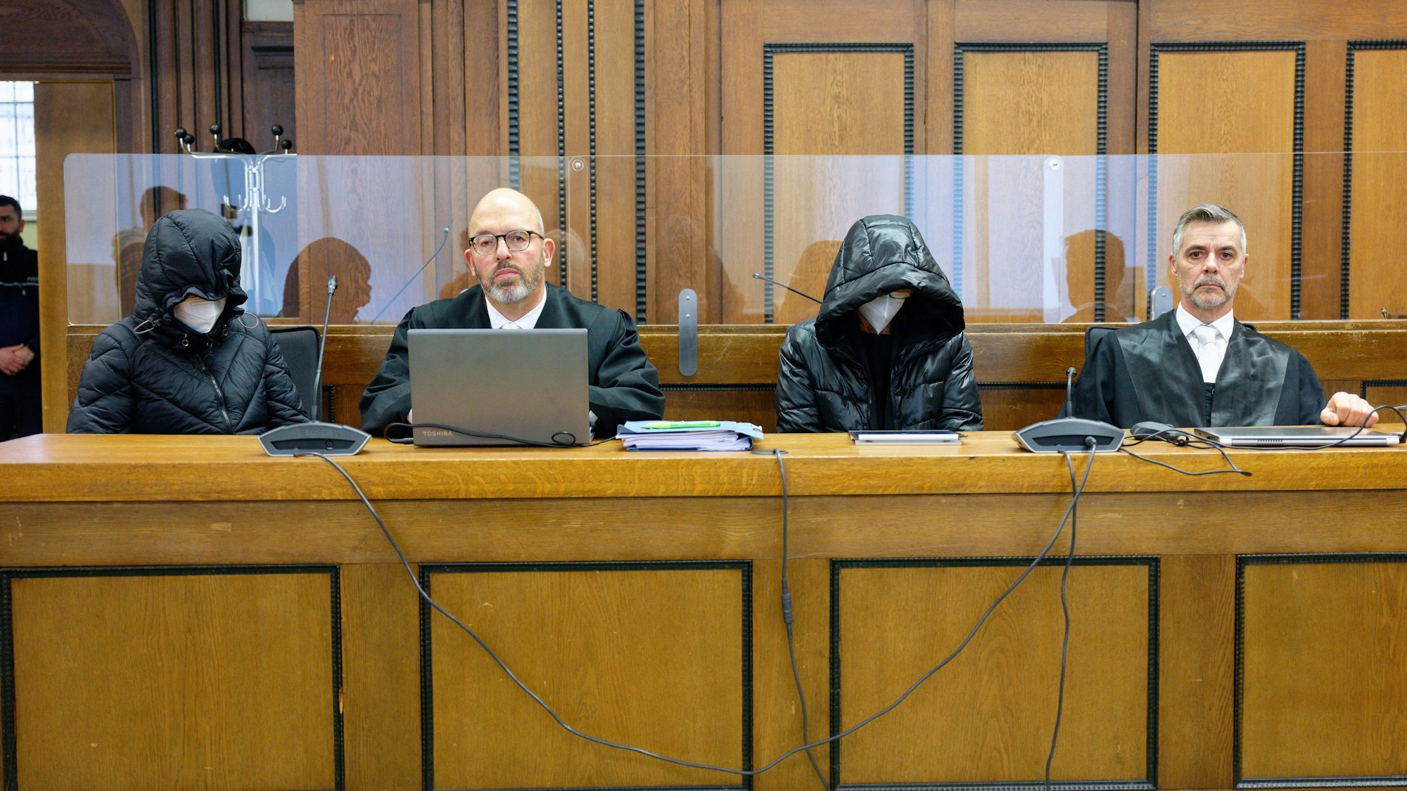 Die beiden Angeklagten und die Rechtsanwälte Lutz Adam (2.v.l) und Marius Kuschka (r) sitzen vor Beginn der Verhandlung im Saal.