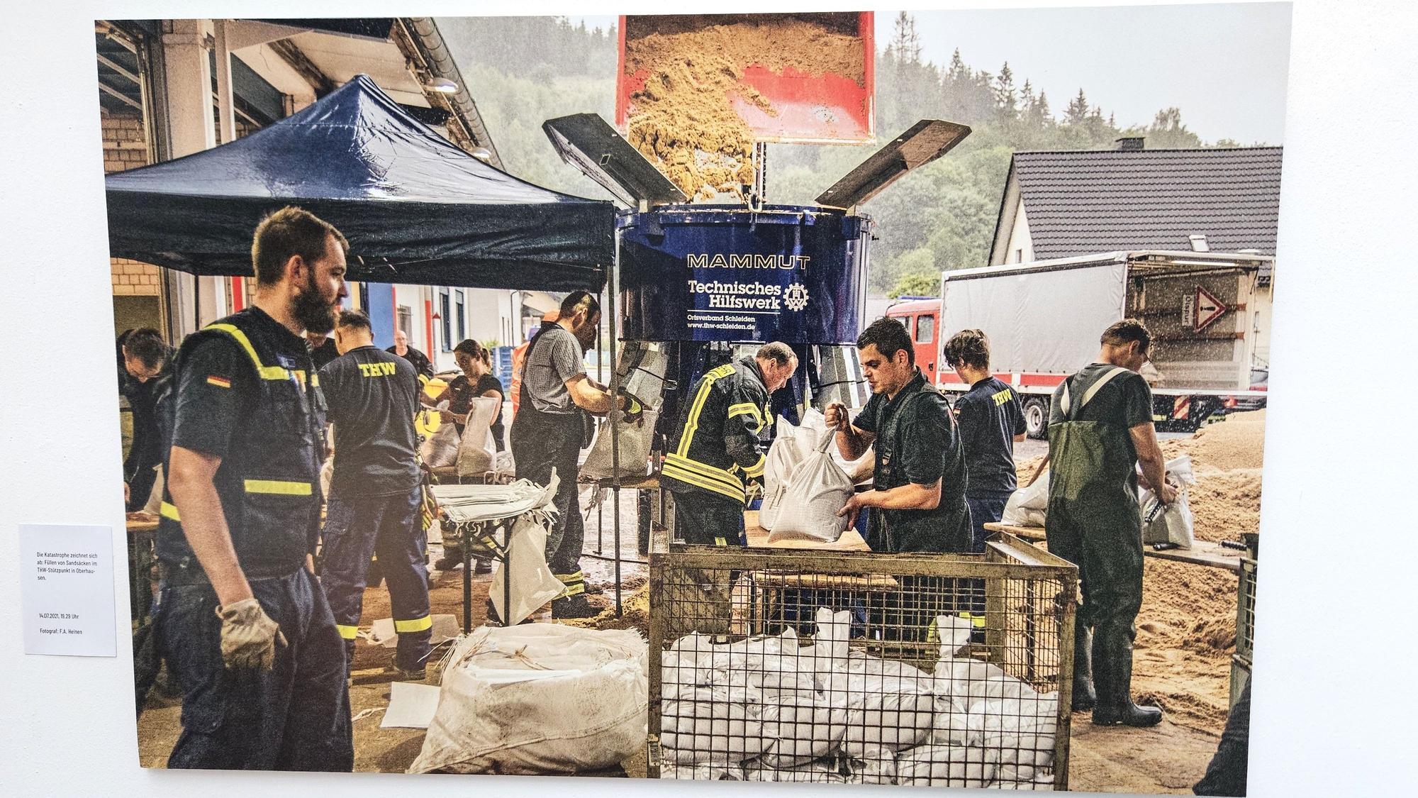 THW-Helfer füllen an Tischen Sandsäcke.