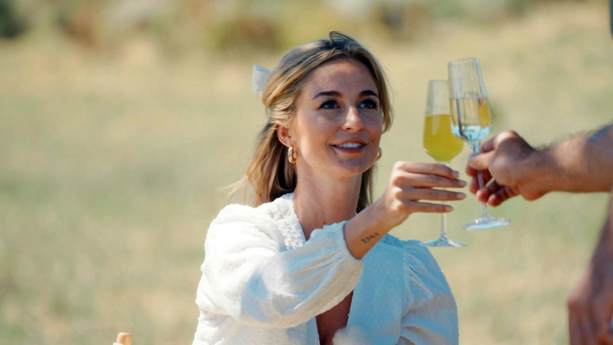 Eine Frau stößt mit einem Glas mit jemandem an.