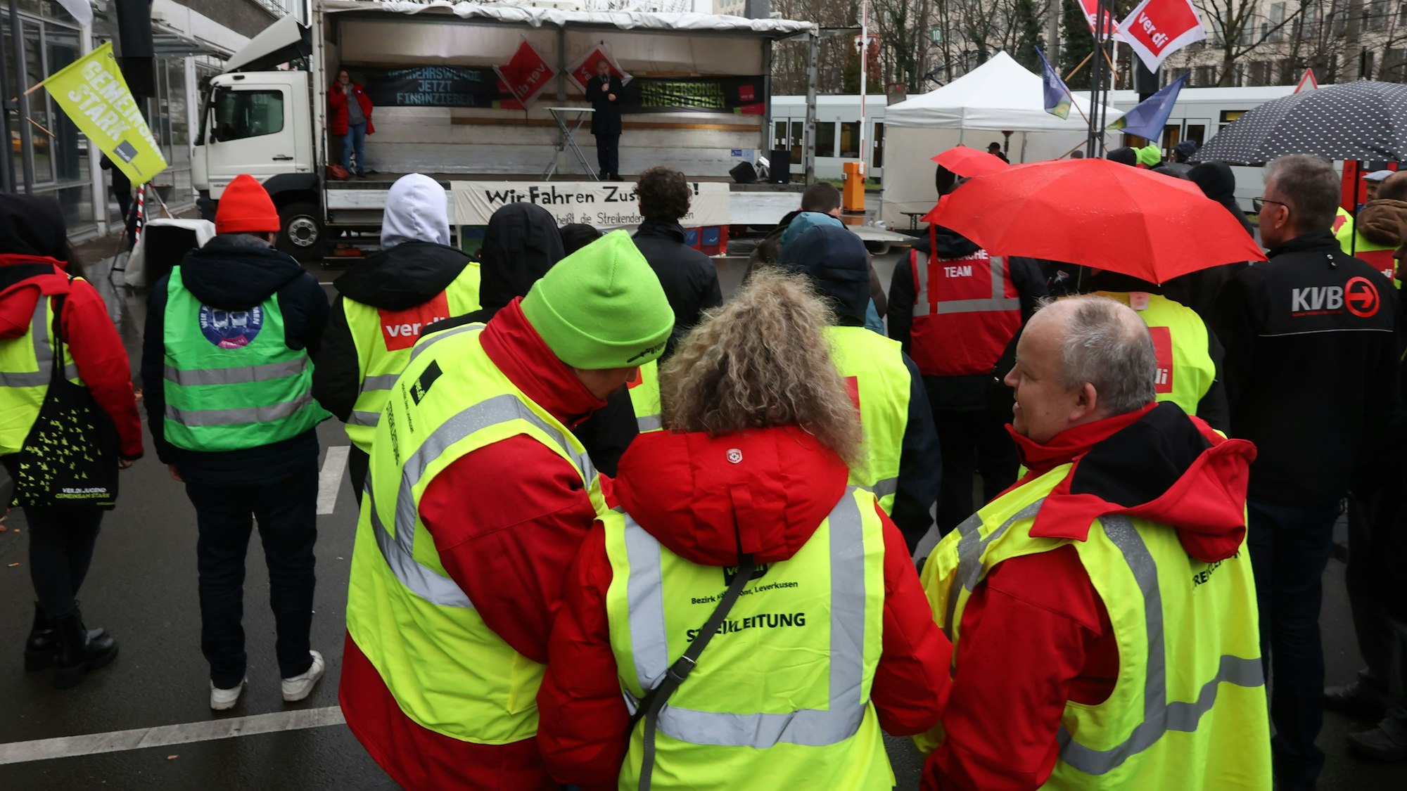 Menschen in Warnwesten stehen vor einer Bühne.