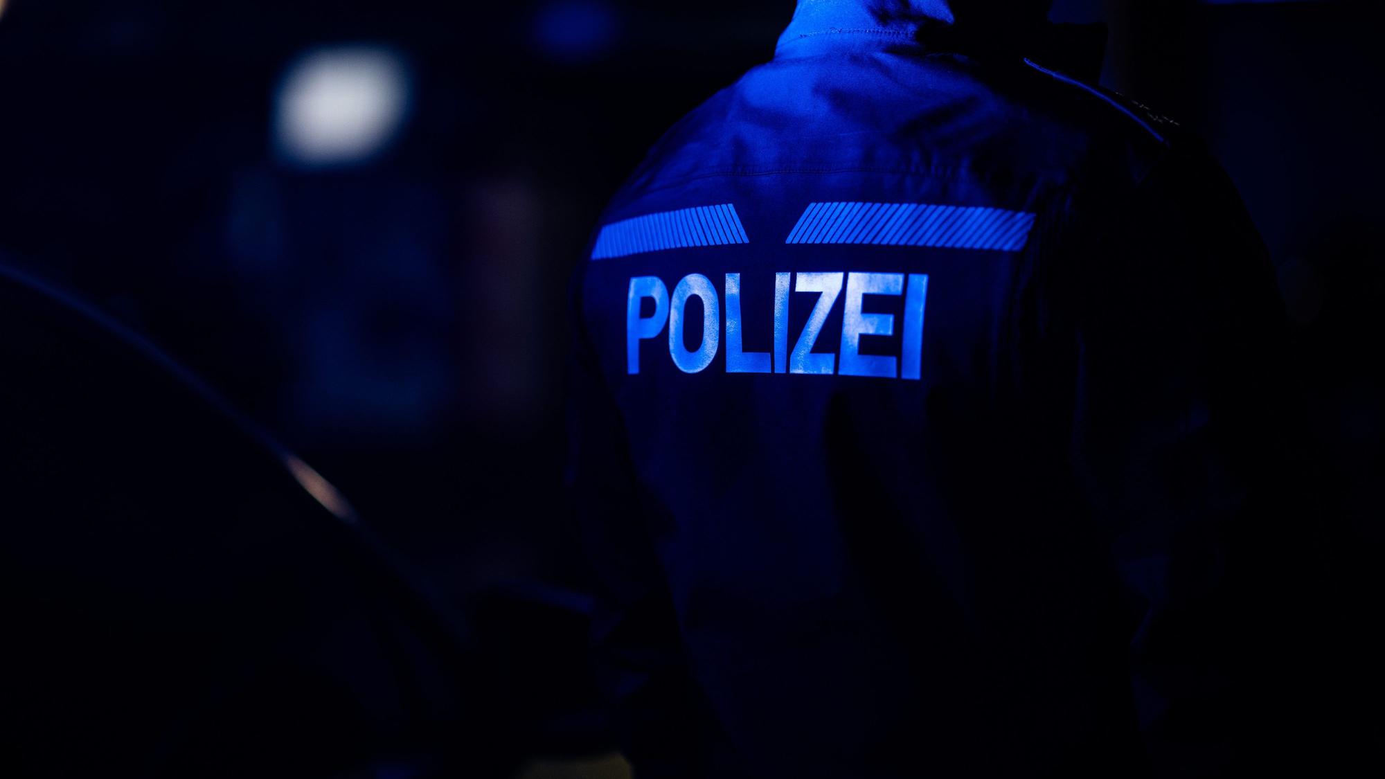 Ein Polizist steht neben einem Polizeiauto.