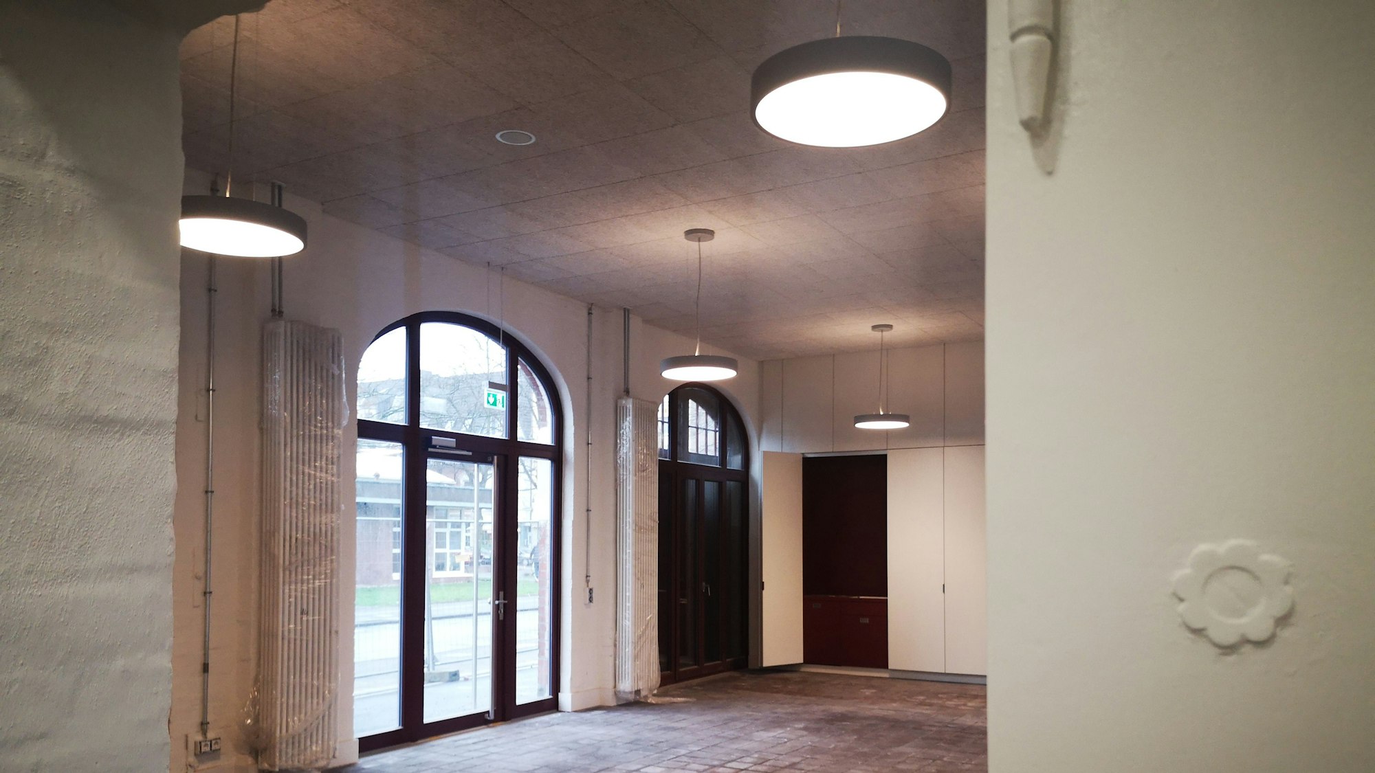 Am rechten Bildrand ein verzierter Türrahmen, dahinter der große Raum der Feuerwache.