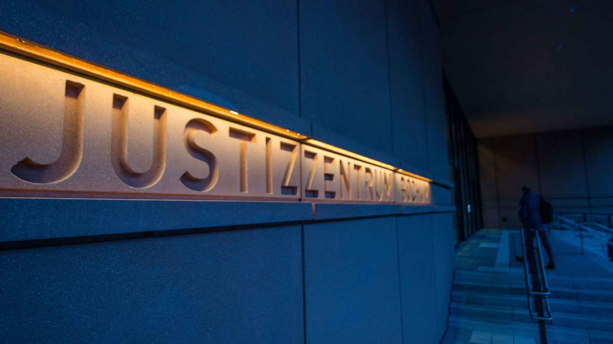 Der Eingangsbereich des neuen Justizzentrums Bochum ist zu sehen, es ist beleuchtet, die Umgebung dunkel.