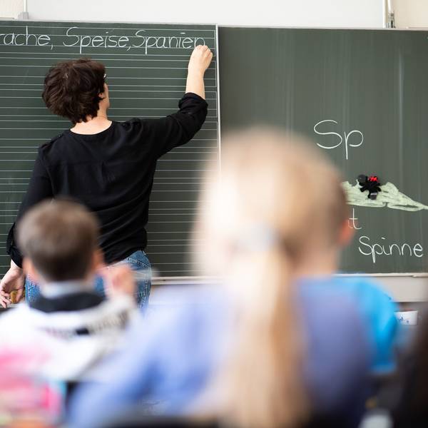 Eine Lehrerin schreibt in einer Grundschule Wörter an eine Tafel.