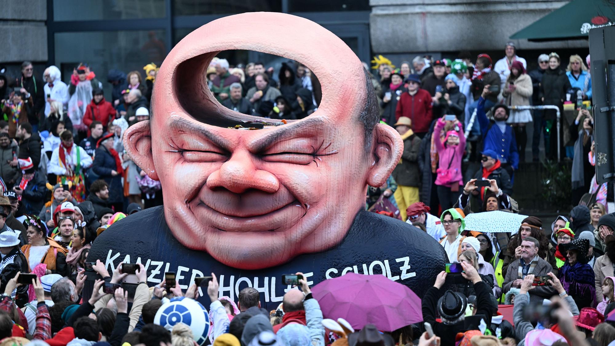 Ein Mottowagen des Düsseldorfer Rosenmontagszugs zeigt eine Büste von Olaf Scholz. Hinter der Stirn des Kanzlers befindet sich allerdings ein Hohlraum, was ihm die Bezeichnung als „Kanzler Hohlaf Scholz“ einträgt.