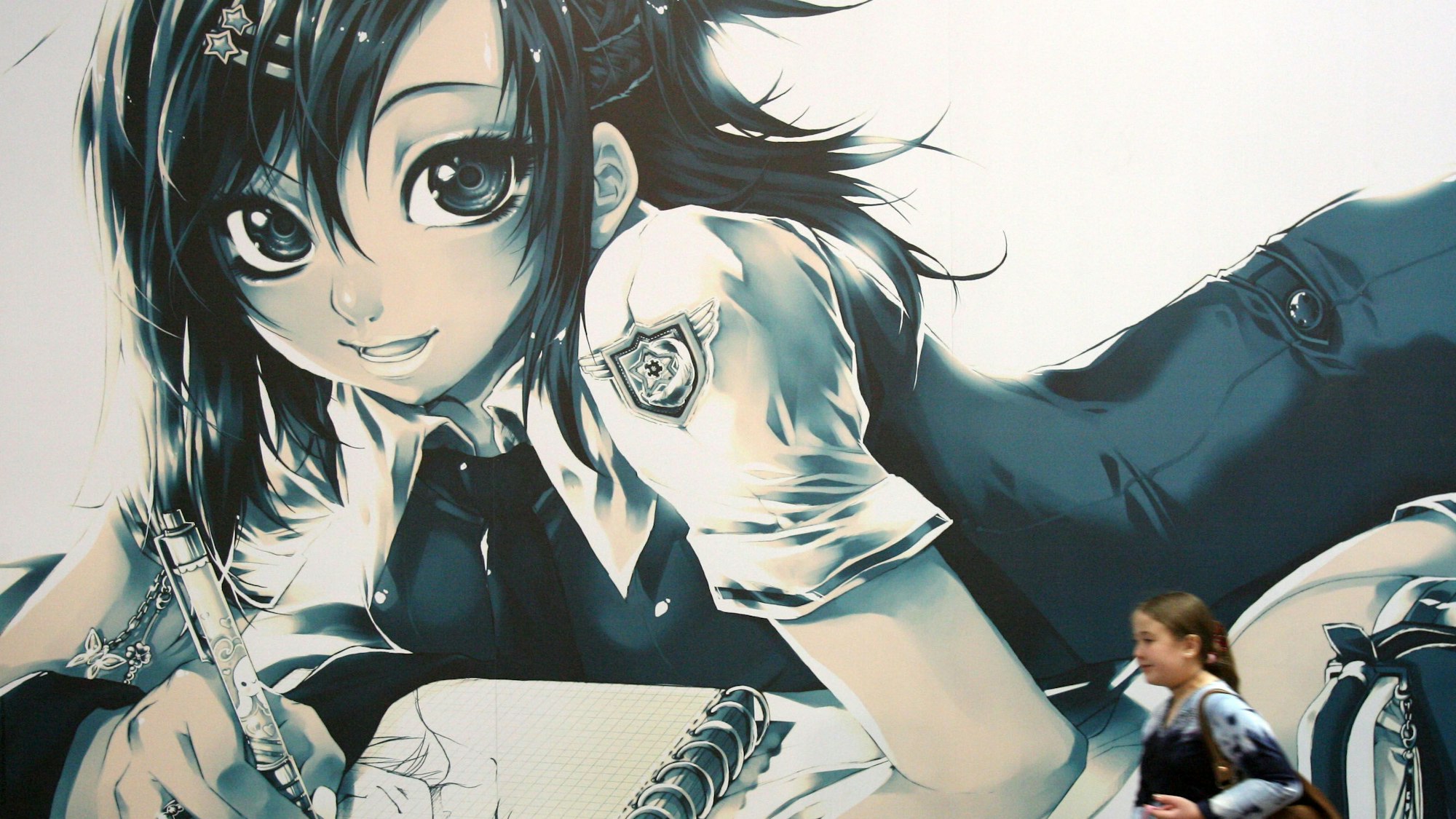 Auf dem Foto ist ein Mädchen zu sehen, das an einer wandfüllenden Zeichnung mit einer Manga-Figur vorbeigeht.