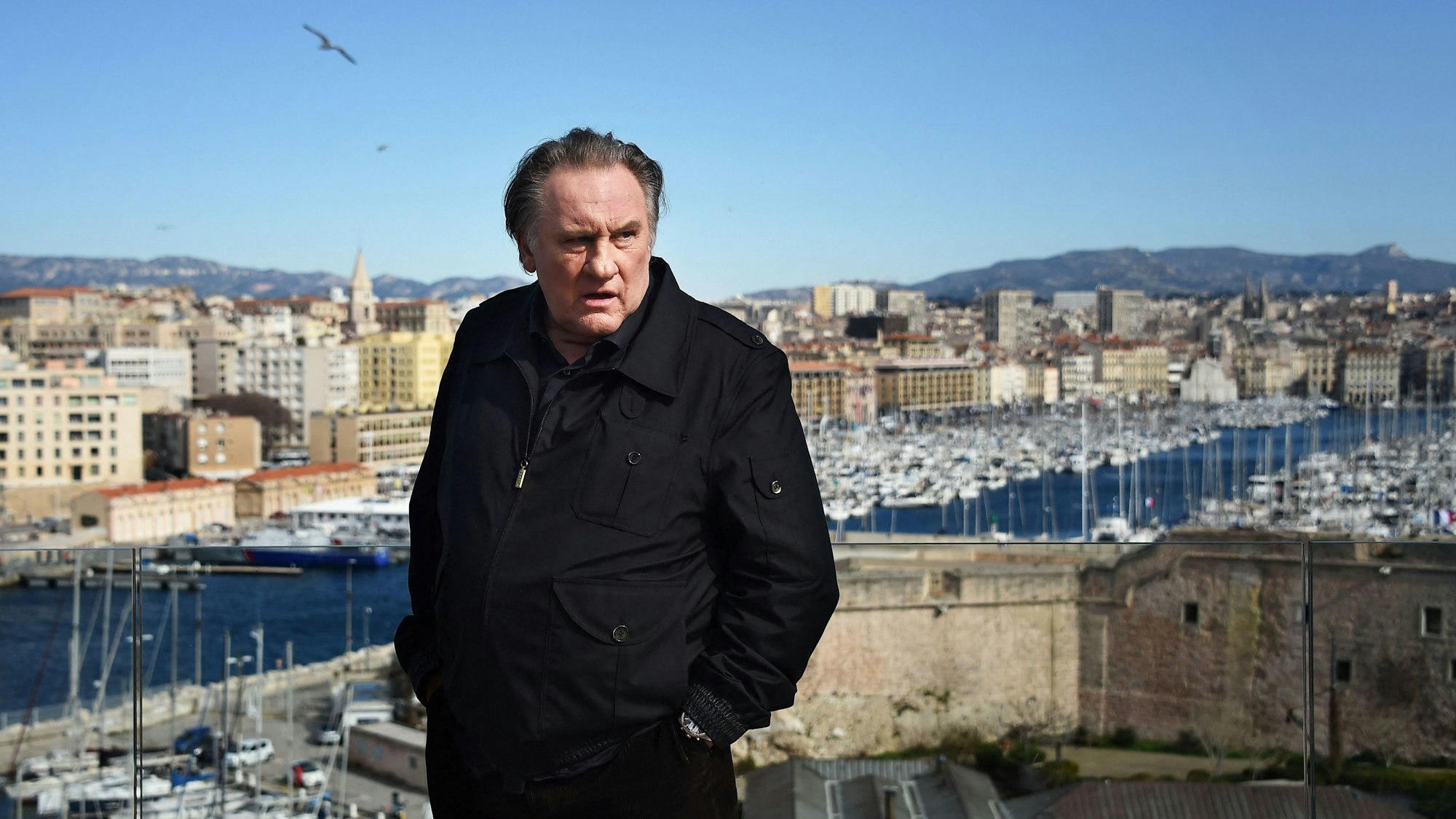 Schauspieler Gérard Depardieu steht in einer Jacke vor einem Hafen-Panorama.(Archivbild)