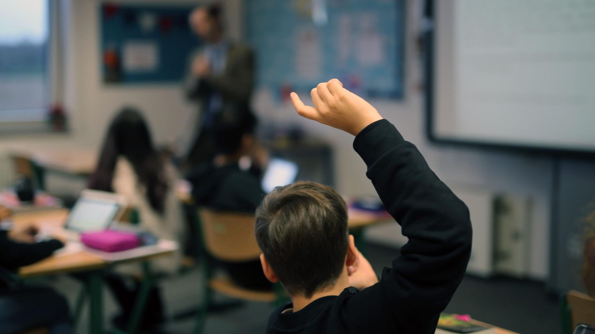 Ein Junge zeigt in einer Klasse auf.