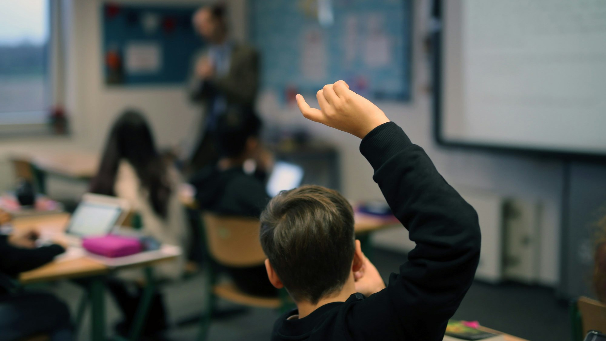 Ein Junge zeigt in einer Klasse auf.