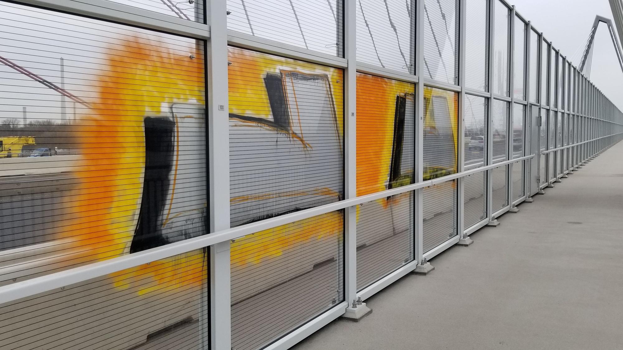 Ein gelbes Graffiti auf einer Glasscheibe der Leverkusener Brücke.