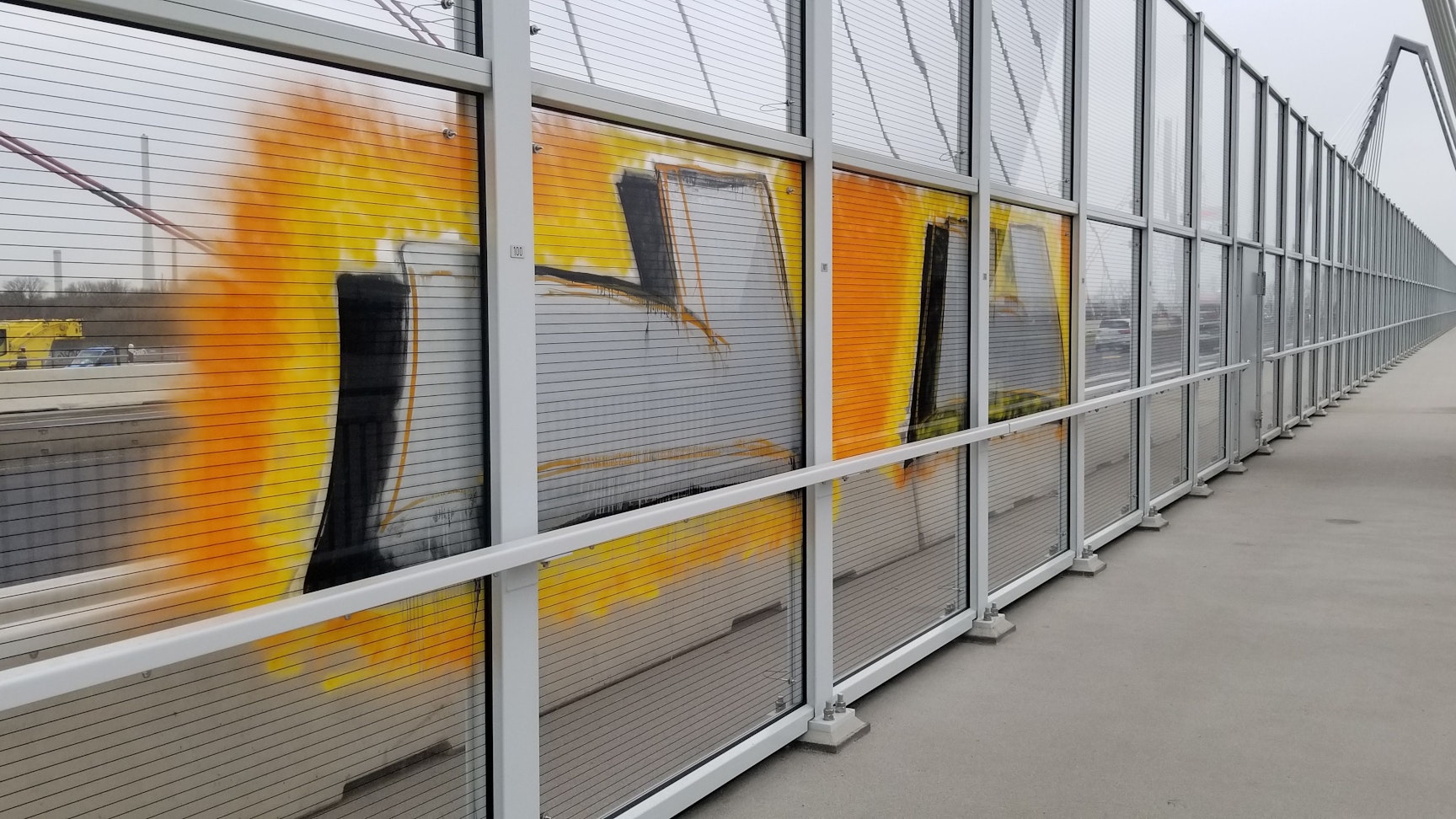 Ein gelbes Graffiti auf einer Glasscheibe der Leverkusener Brücke.