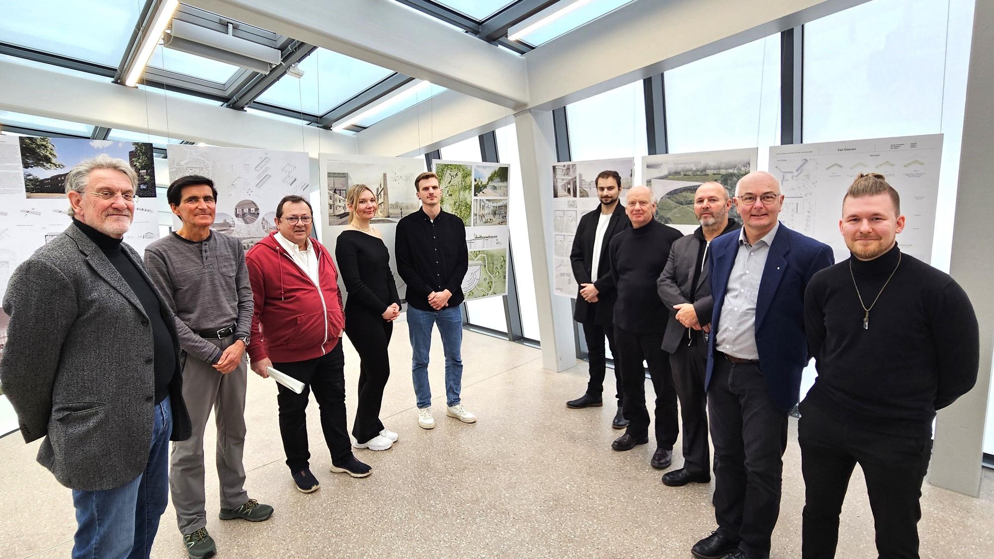 Studierende, Professoren und andere Protagonisten stehen vor den Entwürfen.