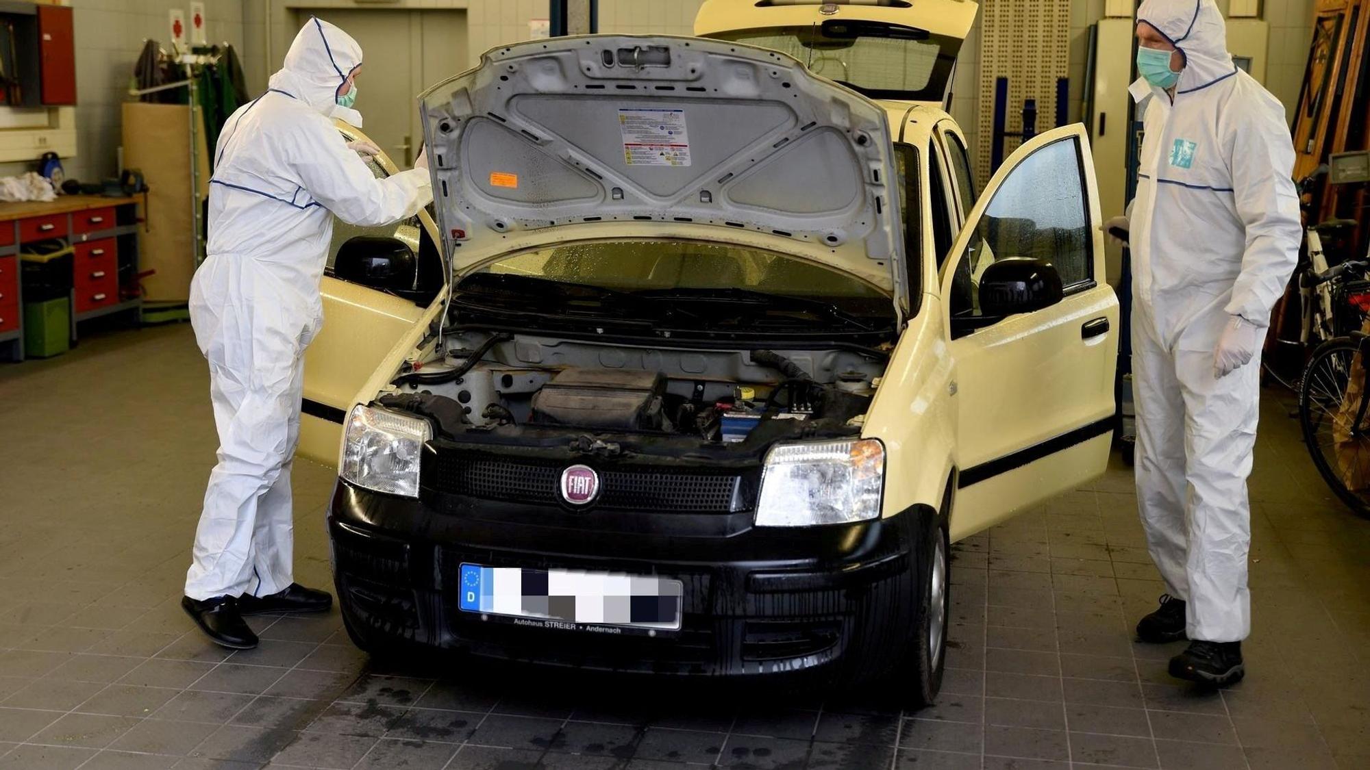 Zwei Männer in weißen Anzügen stehen in einer Werkstatt neben einem Fiat Panda.