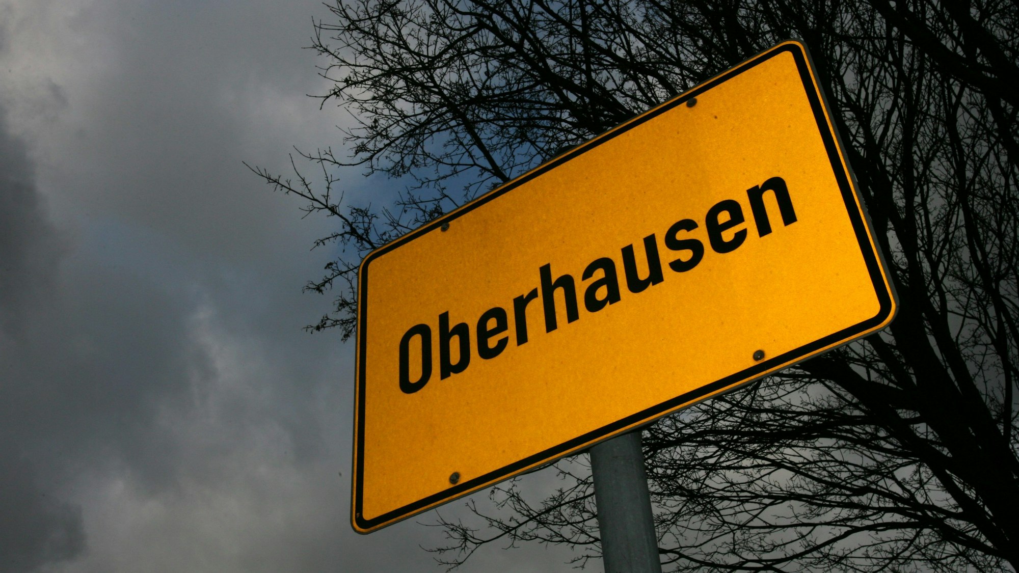 Das Ortsschild von Oberhausen steht am 18.12.2008 vor düsterem Himmel und den dürren, blattlosen Ästen eines Baumes