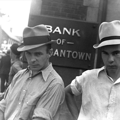 Die Schwarz-Weiß-Aufnahme „Main Street, Morgantown, West Virginia, 1935“ von Walker Evans zeigt zwei Männer, die Hüte tragen und vor einem Bankgebäude stehen.