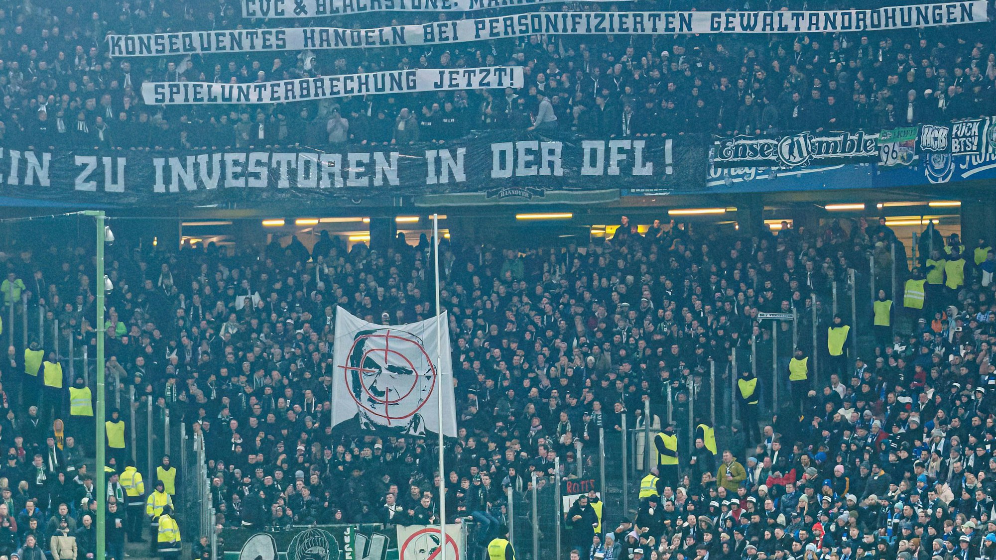 Fans von Hannover 96 zeigen ihren Geschäftsführer Martin Kind im Fadenkreuz, darüber erklären sie mit Spruchbannern die Bedeutung dieser Darstellung.