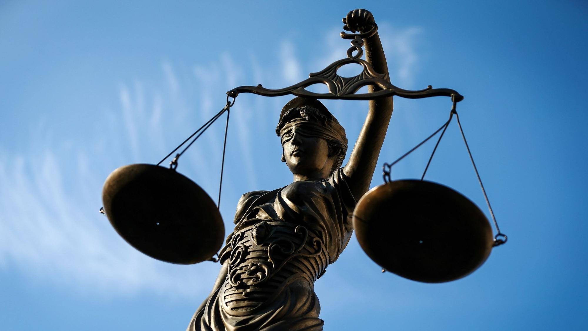 Eine Statue der Justitia hält eine Waage in der Hand.
