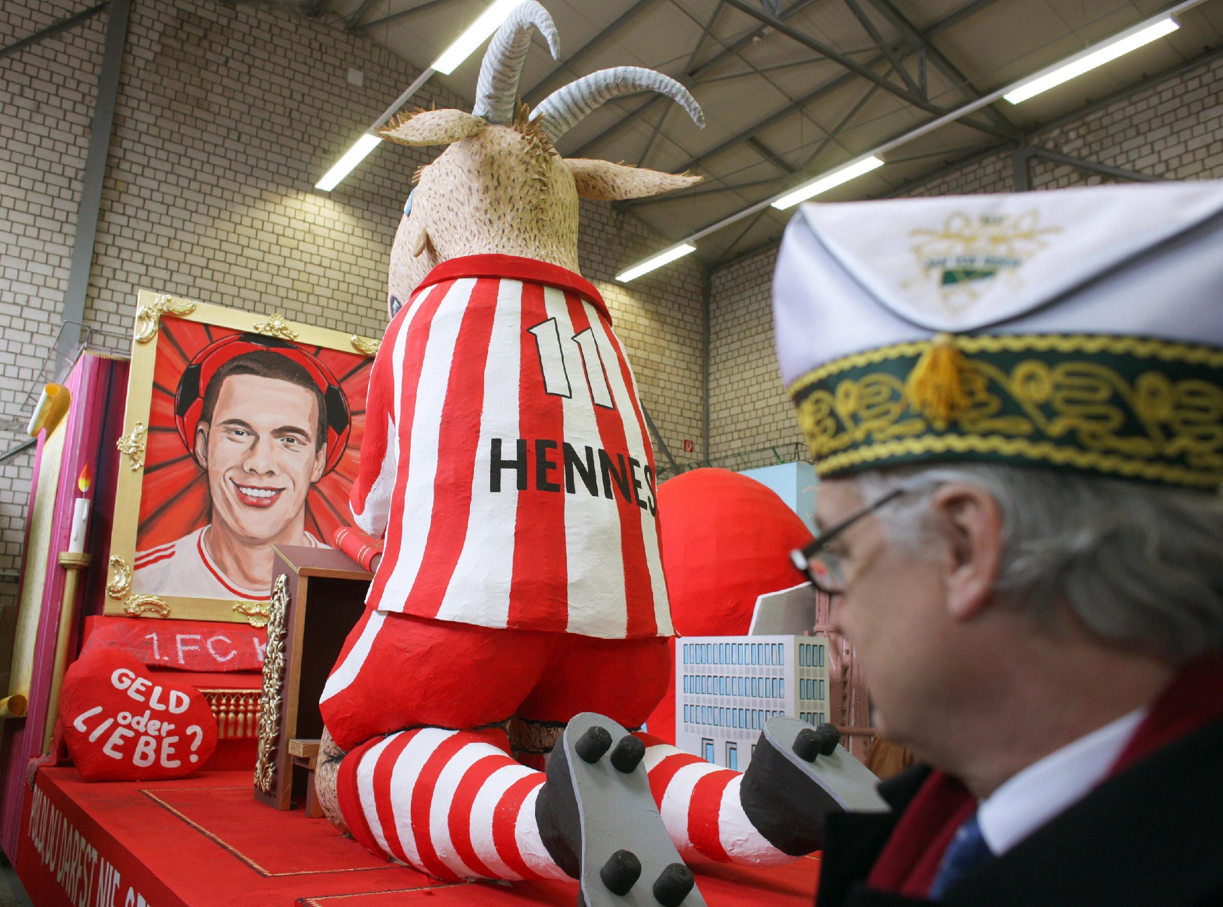 Ein Karnevalswagen, der den Geißbock Hennes betend vor dem Star des 1. FC Köln, Lukas Podolski zeigt, steht am Dienstag (14.02.2012) in einer Halle in Köln.