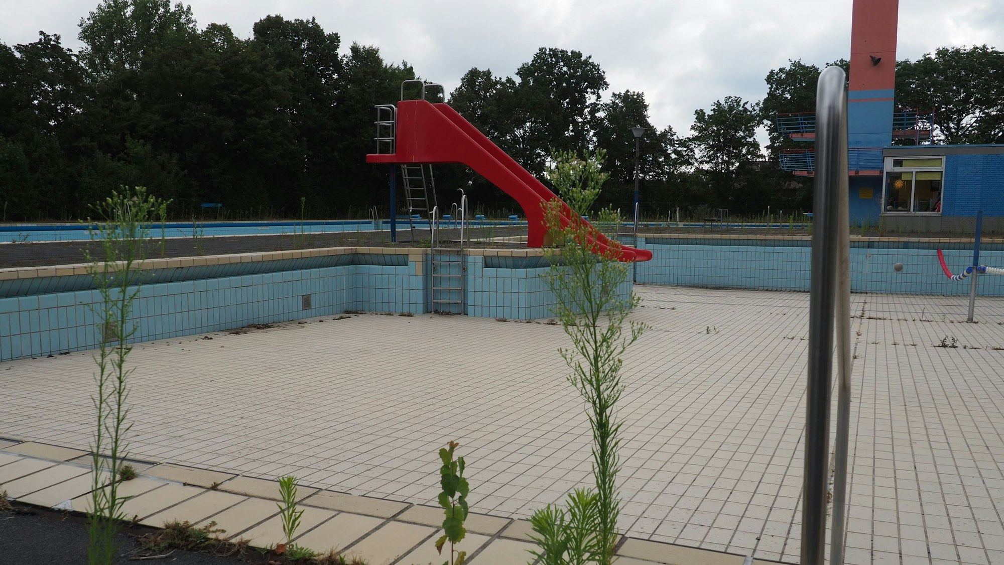Zu sehen ist ein Freibad mit Rutsche ohne Wasser.