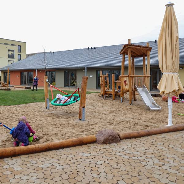 Kinder spielen auf dem Außengelände einer Kindertagesstätte.