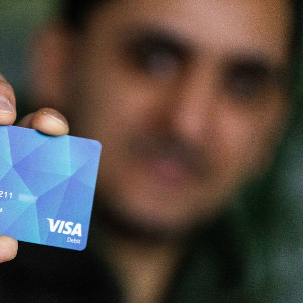 Ein Geflüchteter hält eine Debitkarte in der Hand (Symbolbild).