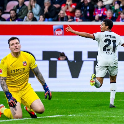 Leverkusens Amine Adli (r) jubelt nach seinem Tor zum 0:2. Heidenheims Torwart Kevin Müller (l) reagiert unzufrieden.