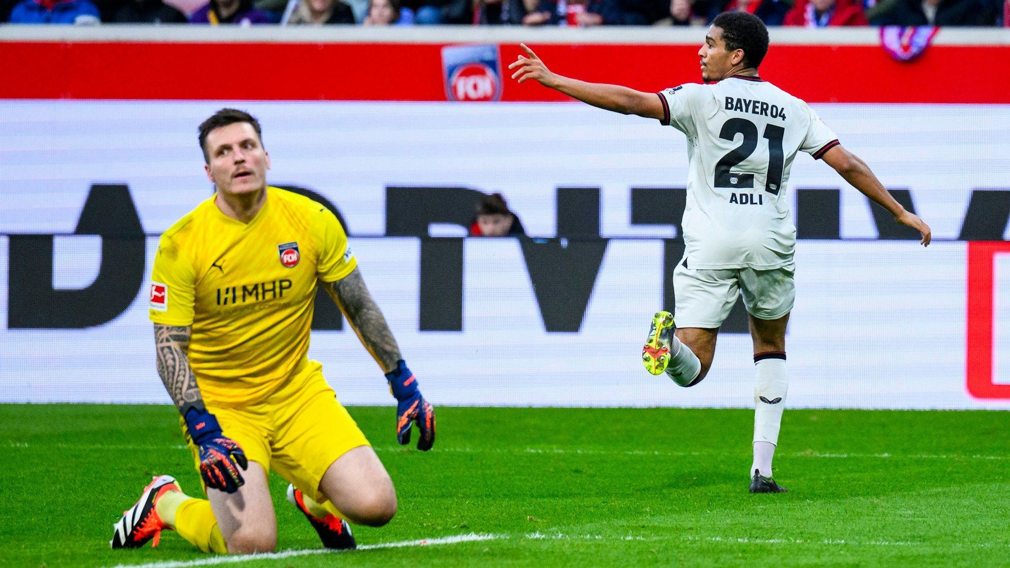 Leverkusens Amine Adli (r) jubelt nach seinem Tor zum 0:2. Heidenheims Torwart Kevin Müller (l) reagiert unzufrieden.