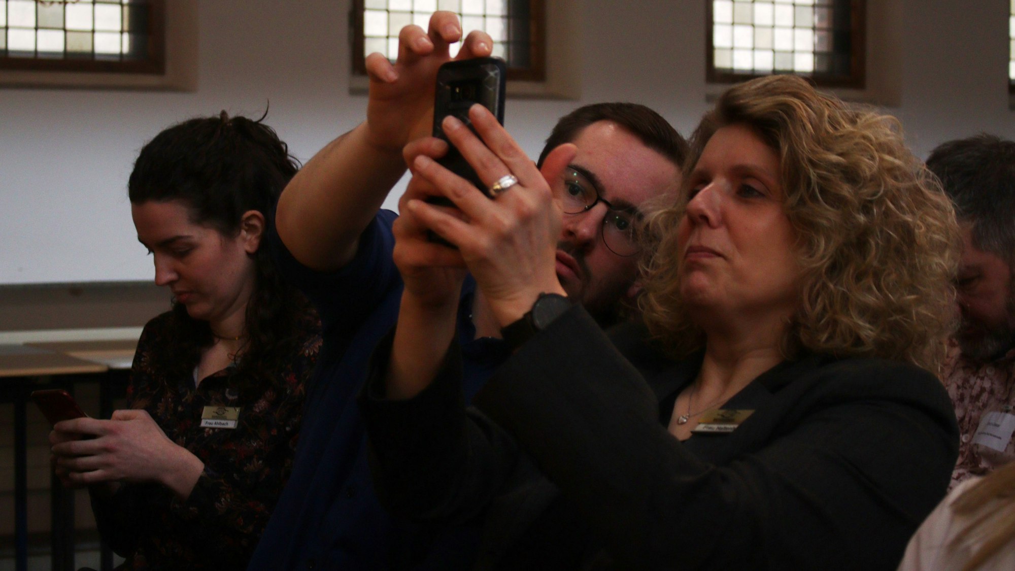 Wirtschaftsförderer Dennis Heinen und Carmen Haltenhof schauen auf ein Handy, das sie in die Höhe hält.