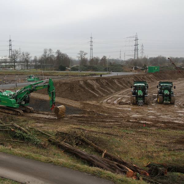 Großbaustelle mit zwei Baugruben sowie grünen Baggern und Traktoren.