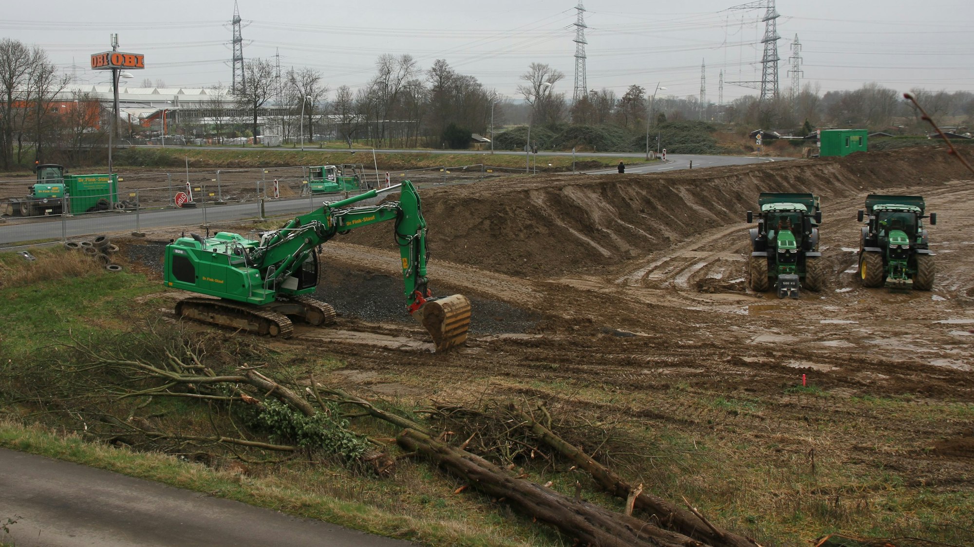 Großbaustelle mit zwei Baugruben sowie grünen Baggern und Traktoren.