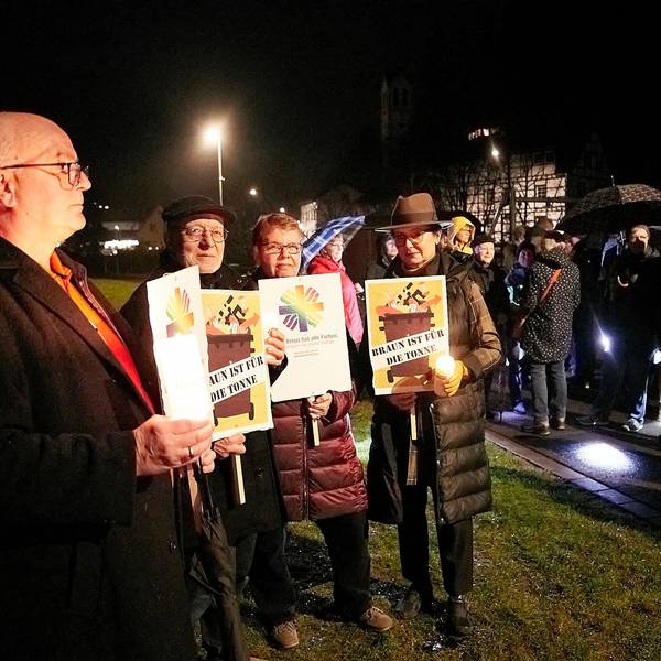 Teilnehmer einer Mahnwache gegen rechts halten Plakate vor dem Körper.