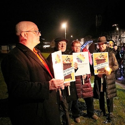 Teilnehmer einer Mahnwache gegen rechts halten Plakate vor dem Körper.