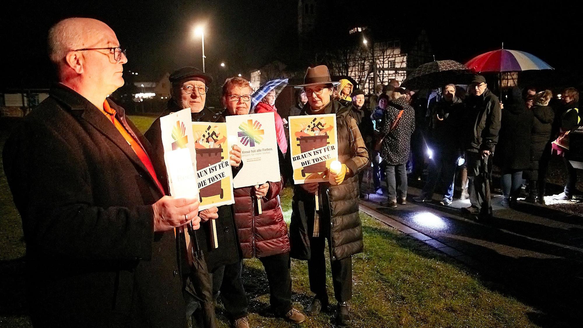 Teilnehmer einer Mahnwache gegen rechts halten Plakate vor dem Körper.
