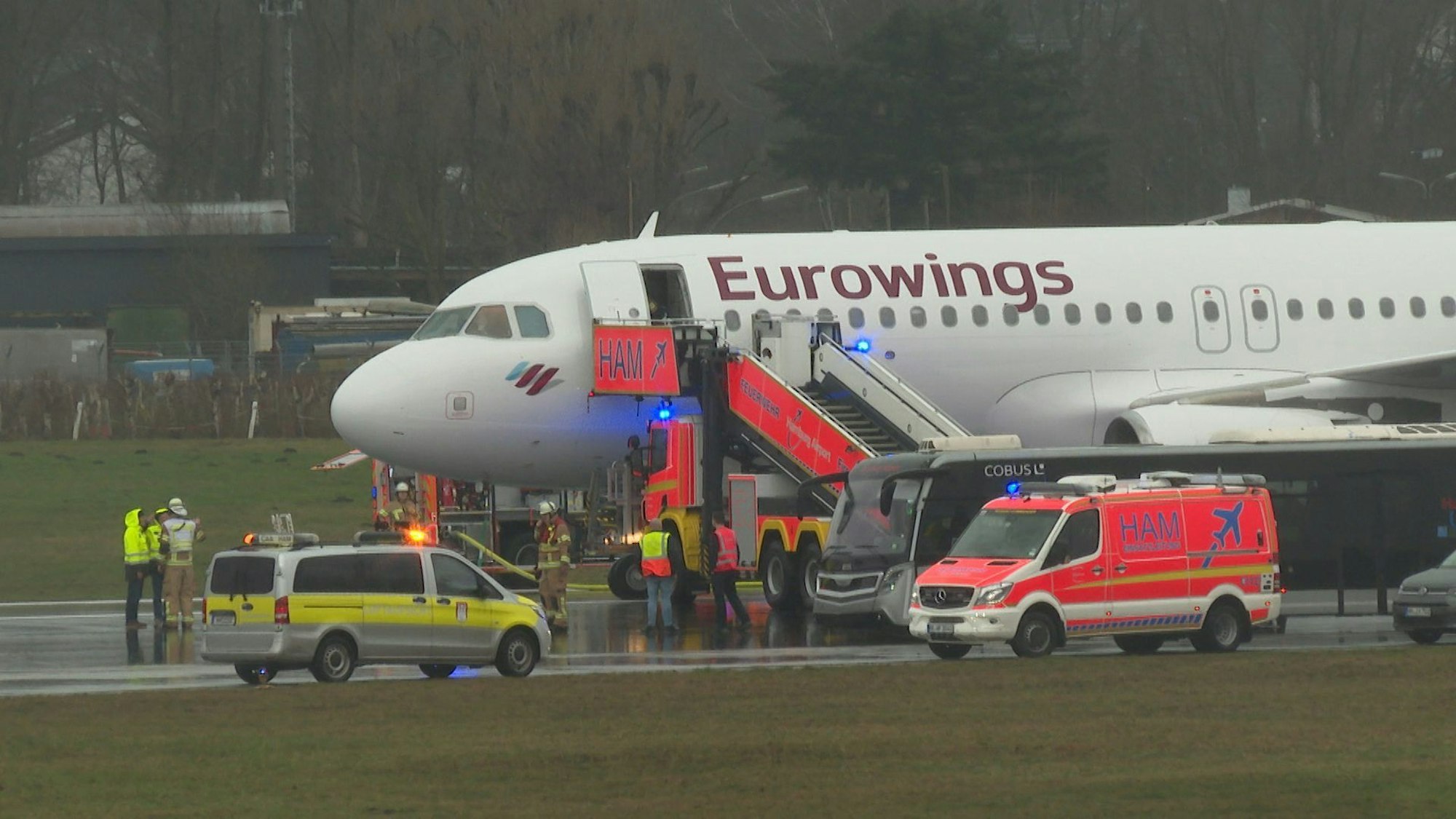 Helfer stehen auf dem Flughafengelände an einem Flugzeug.