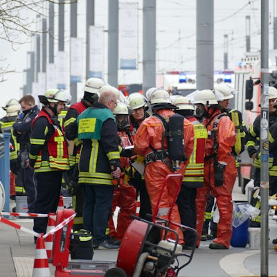 Feuerwehrleute in Schutzanzügen erkunden die Lage am Brückenforum in Bonn.