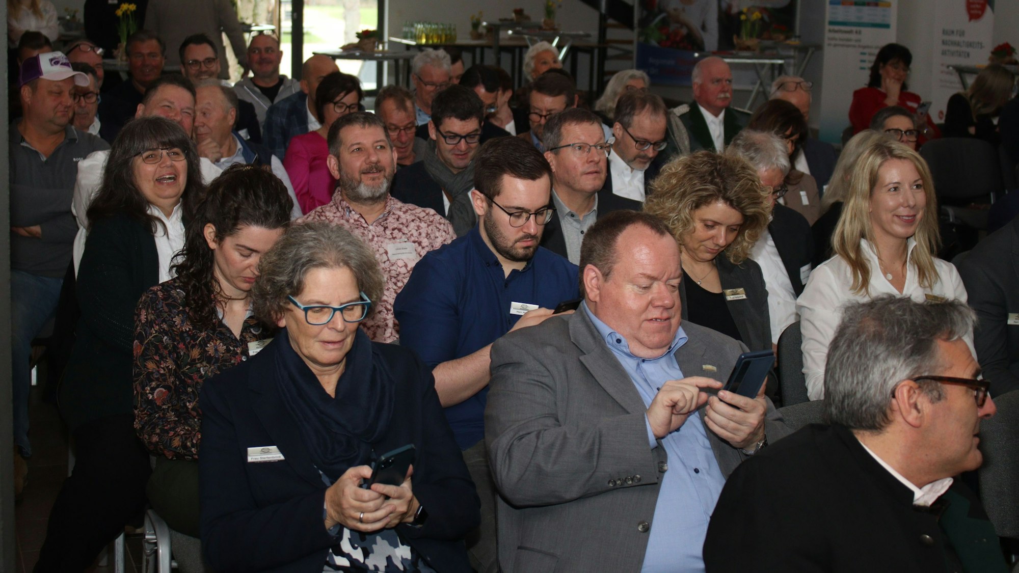 Die Gäste des Neujahrsempfangs nehmen mit ihren Smartphones an einem Quiz teil.