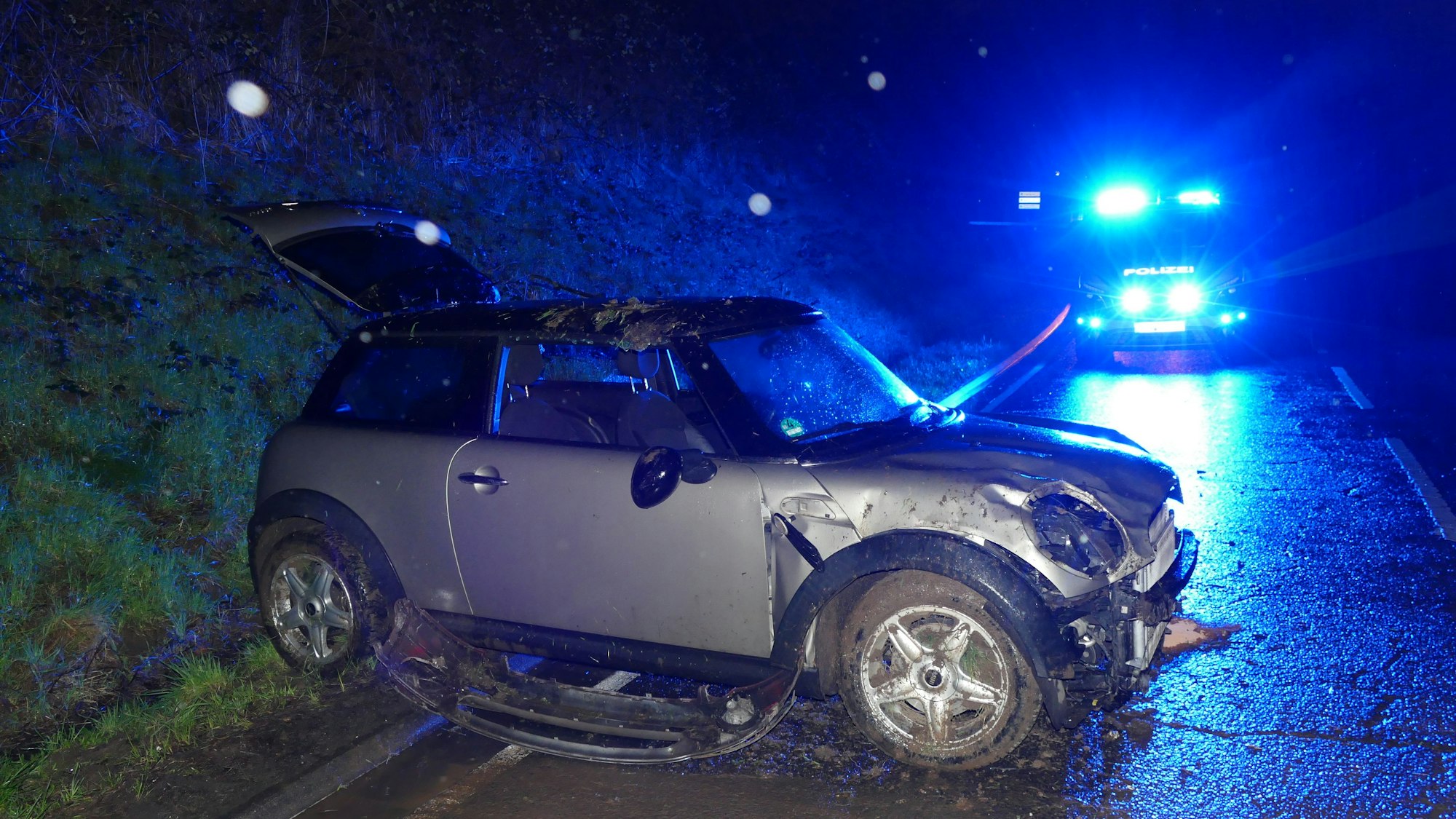 Ein beschädigter Mini steht quer auf einer Straße.