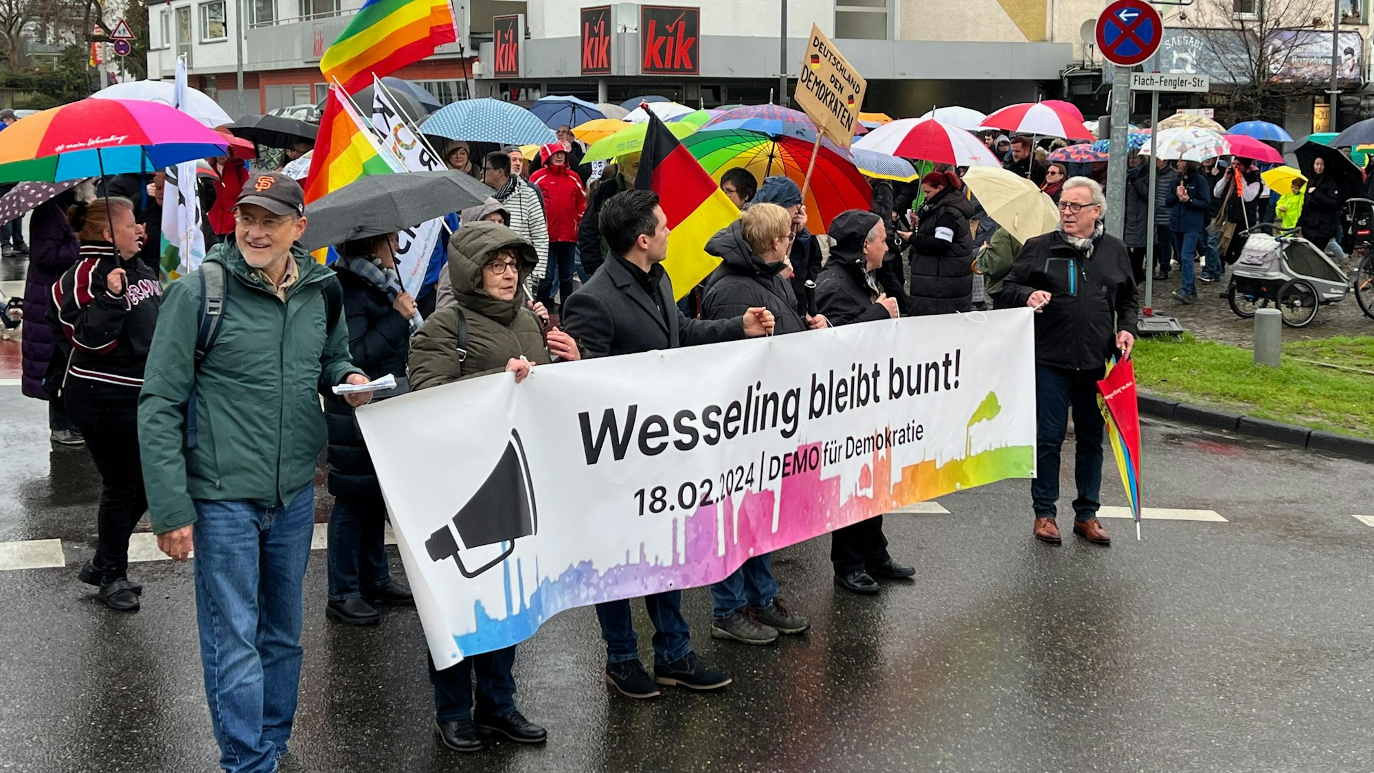 Auf dem Foto sind Teilnehmer der Demonstration gegen Rechtsextremismus in Wesseling zu sehen. Auf einem Banner steht „Wesseling bleibt bunt!“