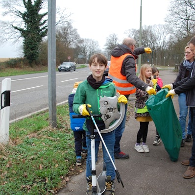Ein Kind mit einer abgebrochenen Radkappe in der Hand und weitere Müllsammler.