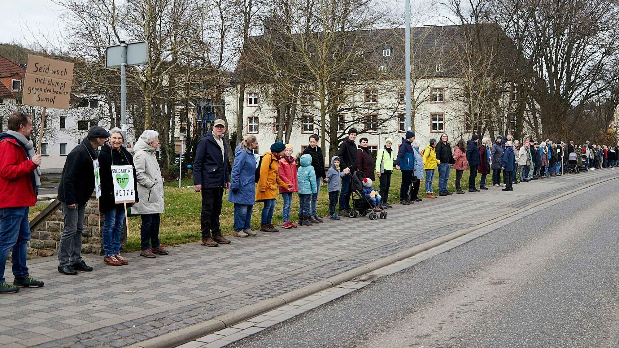 Teilnehmer einer Menschenkette zwischen Verteilerkreis und Olefbrücke in Schleiden. Einige haben Plakate dabei.