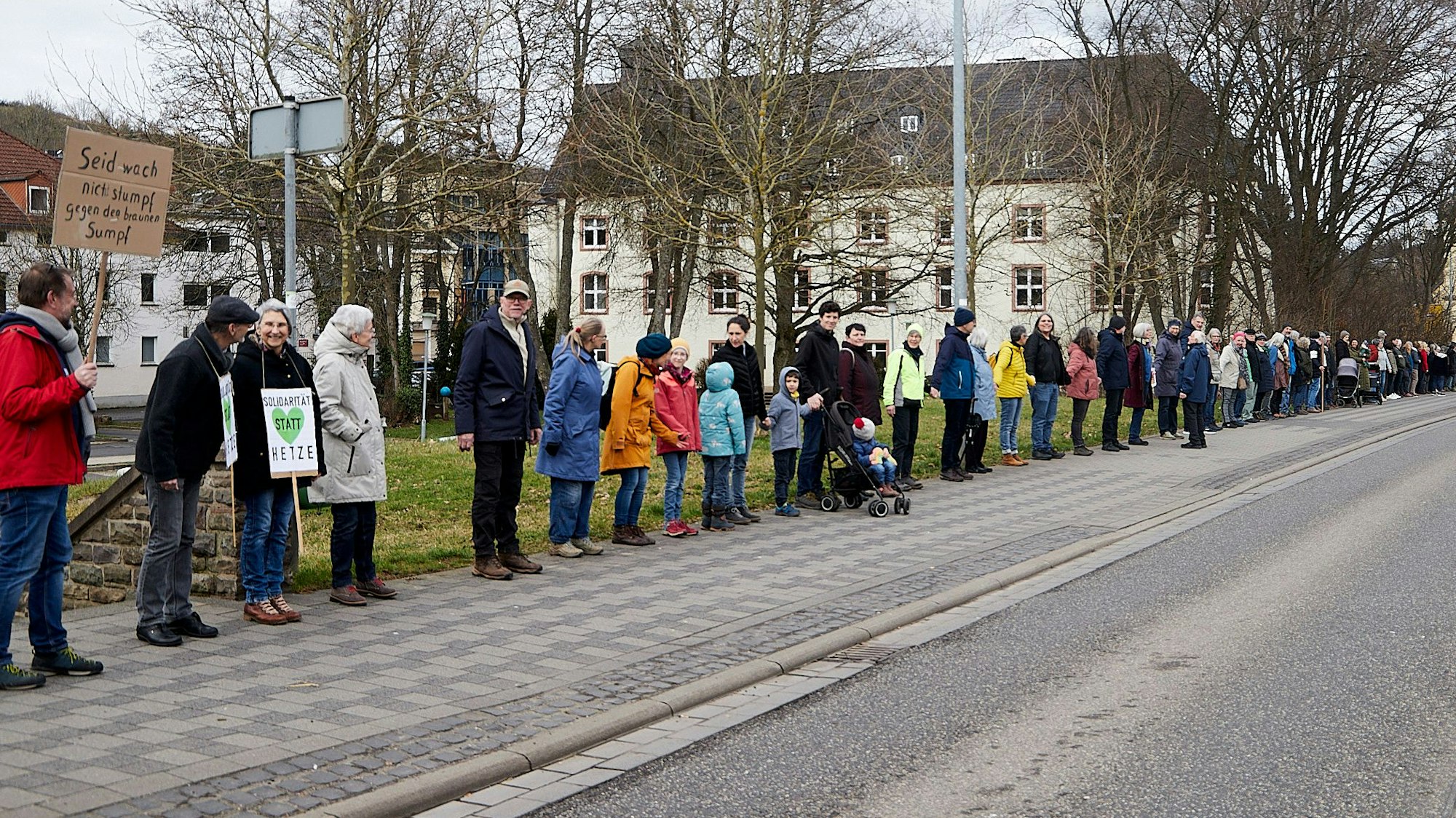 Teilnehmer einer Menschenkette zwischen Verteilerkreis und Olefbrücke in Schleiden. Einige haben Plakate dabei.